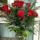 A vase filled with red roses and greenery.