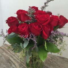 A vase filled with red roses on top of a table.