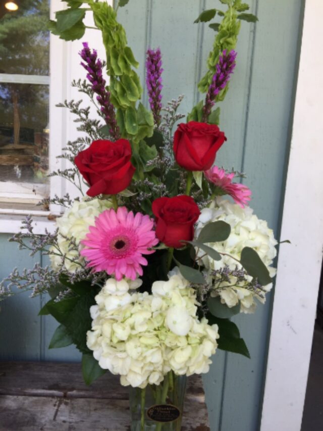 A bouquet of flowers sitting on the door step.