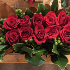 A bouquet of red roses in a wooden box.