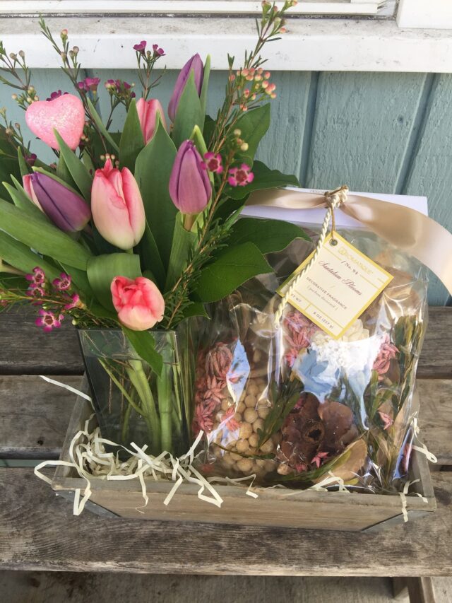 A wooden crate with flowers and nuts in it.