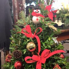 A christmas tree with red ribbon and ornaments.