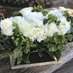 A wooden box filled with white flowers on top of a table.