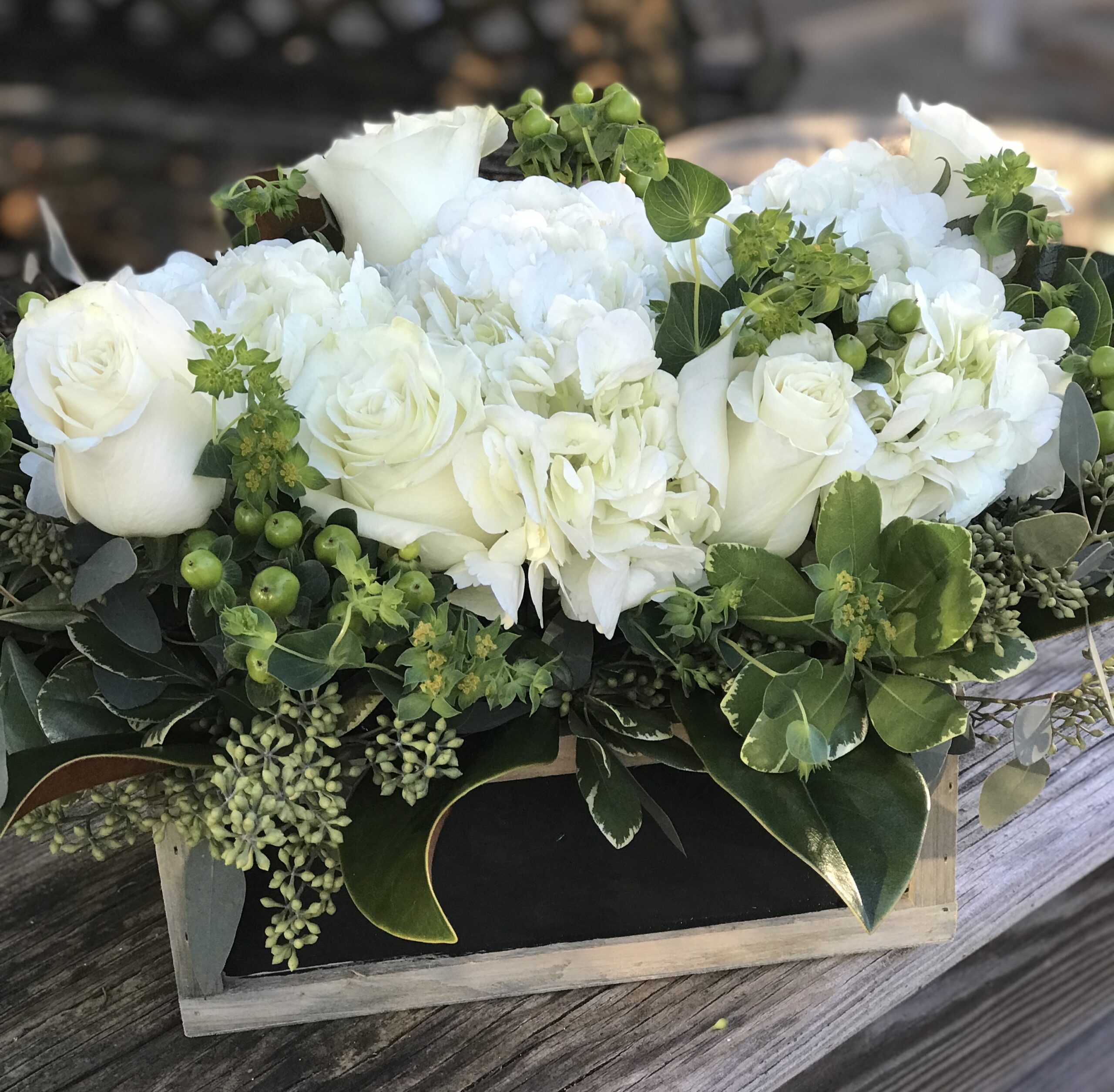 A wooden box filled with white flowers on top of a table.