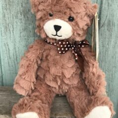 A brown teddy bear sitting on top of a wooden table.