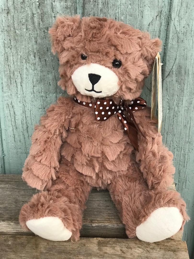 A brown teddy bear sitting on top of a wooden table.