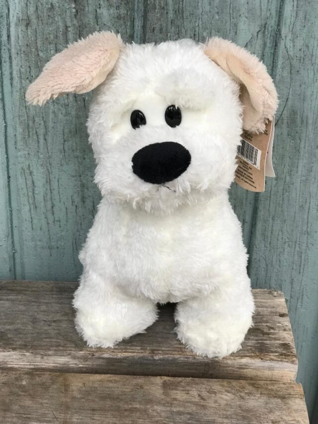 A white stuffed dog with a brown ear tag.