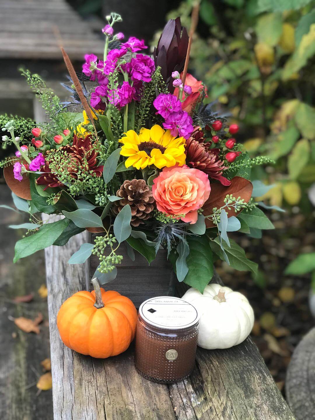 Autumn floral arrangement with candle and pumpkins.