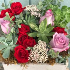 Roses, succulents, and greenery in wooden box.