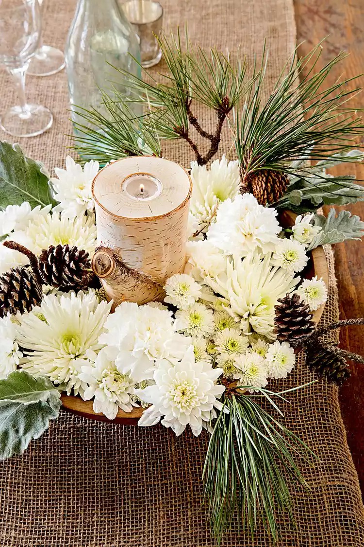 Candle centerpiece with flowers and pinecones.